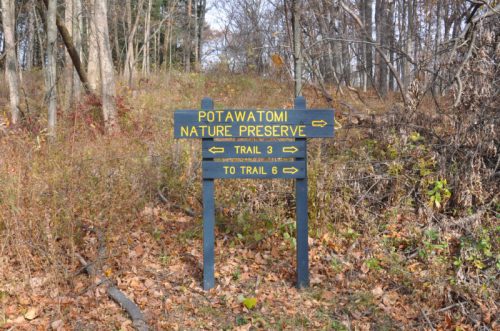 Signpost at Potawatomi Nature Preserve indicating directions to Trail 3 and Trail 6 among autumn foliage.