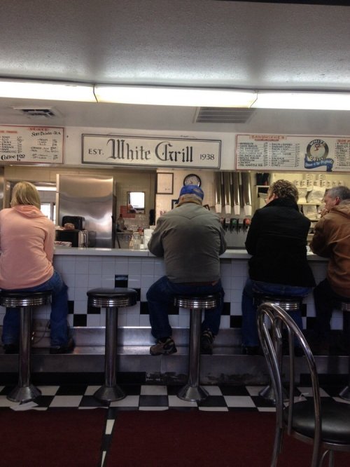 A diner scene showing people sitting at a counter in a retro-style restaurant with a sign reading "White Grill."