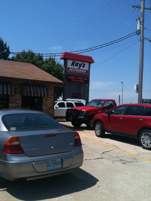 A parking lot with several cars in front of Ray's Restaurant, featuring a sign advertising lunch specials.