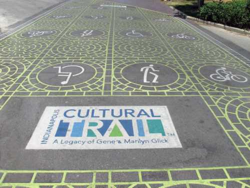 Colorful pavement design featuring symbols for biking, walking, and accessibility, with "Indianapolis Cultural Trail" logo.