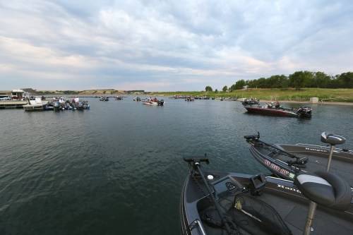 Boats on a calm lake under a cloudy sky, with several fishing boats in the distance.