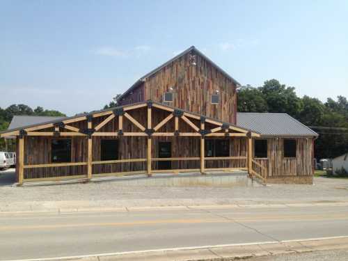 A rustic wooden building with a sloped roof and large front porch, set against a clear blue sky.