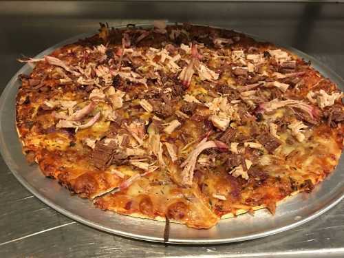 A freshly baked pizza topped with shredded meat and herbs on a silver tray.