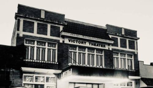 Historic Victory Theater building with a classic facade, featuring large windows and decorative brickwork.