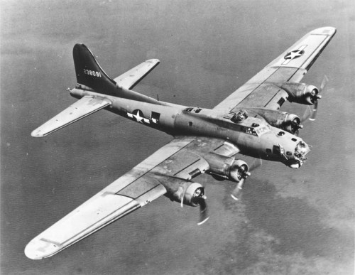 A vintage B-17 bomber flying over the ocean, showcasing its distinctive wings and propellers.