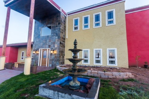 A colorful building with a stone fountain in the foreground, featuring large windows and a welcoming entrance.