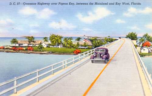 A vintage postcard depicting a car driving on the Overseas Highway over Pigeon Key, Florida, with palm trees and houses.