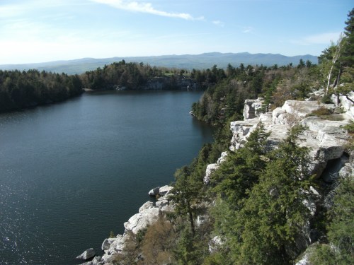 A serene lake surrounded by rocky cliffs and lush trees under a clear blue sky.