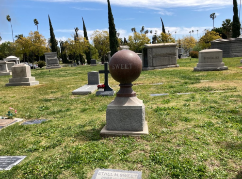 A cemetery scene featuring a prominent gravestone with the name "Sweet" and a spherical monument in the foreground.