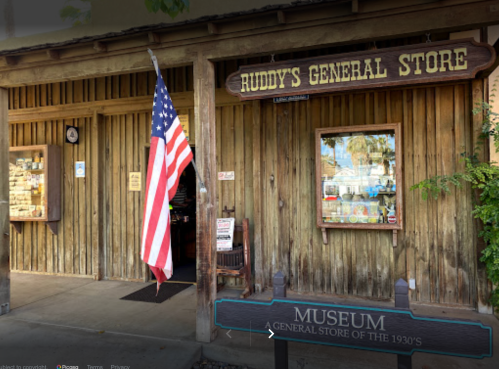 Exterior of Ruddy's General Store with an American flag and a sign for a museum showcasing the 1930s.