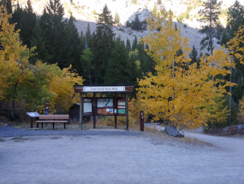 Entrance to Lost Creek State Park, surrounded by vibrant autumn foliage and a gravel path leading into the park.
