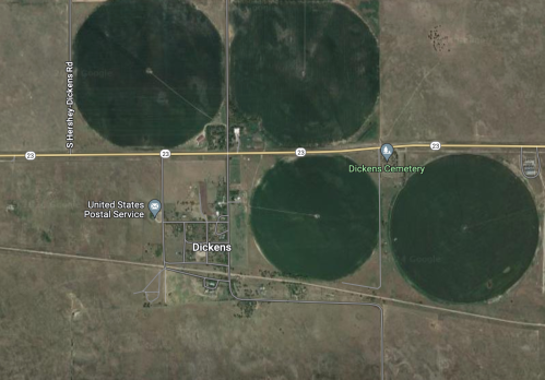 Aerial view of Dickens, Texas, featuring circular agricultural fields and a nearby cemetery.