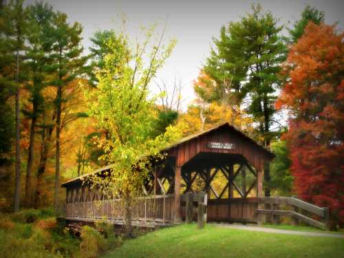 A wooden covered bridge surrounded by vibrant autumn trees in a serene landscape.