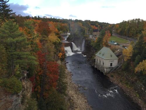 A scenic view of a waterfall surrounded by autumn foliage and a historic building by the riverbank.