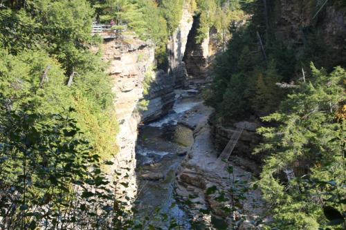 A scenic view of a narrow canyon with a river flowing through, surrounded by lush greenery and rocky cliffs.