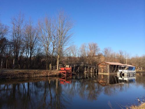 A serene landscape featuring a calm river, a wooden dock, and bare trees under a clear blue sky.