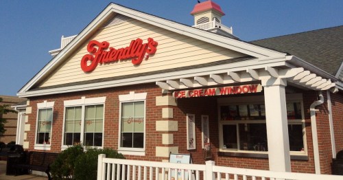 Exterior of a Friendly's restaurant featuring a red sign and an ice cream window, with a clear blue sky above.