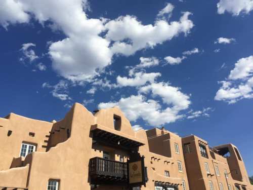 Adobe-style building under a blue sky with fluffy white clouds.