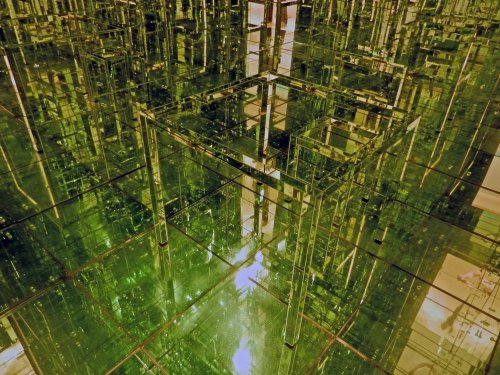 A reflective, green-tinted maze of glass-like structures creating a complex, geometric pattern.