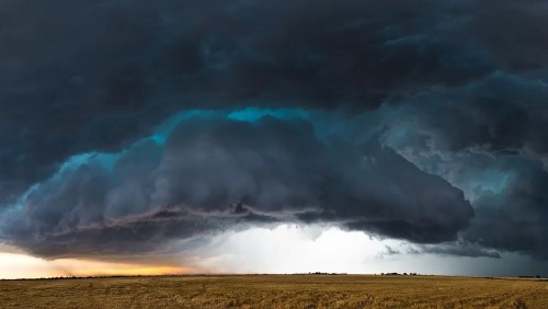 Dramatic storm clouds loom over a golden field, with dark shades contrasting against a lighter horizon.