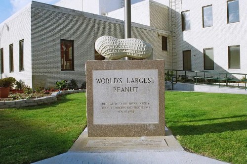 A large peanut sculpture atop a stone pedestal, labeled "World's Largest Peanut," in front of a building.
