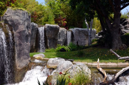 A serene landscape featuring cascading waterfalls, lush greenery, and smooth rocks in a tranquil setting.