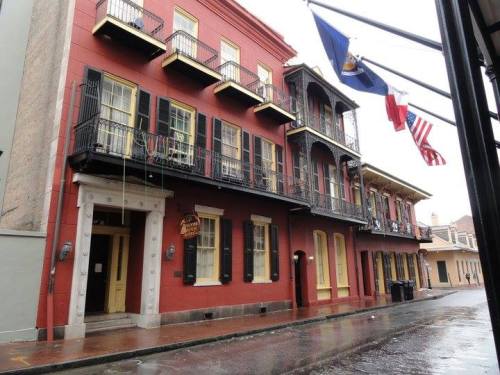 Historic red building with balconies, flags, and a wet street in a charming urban setting.