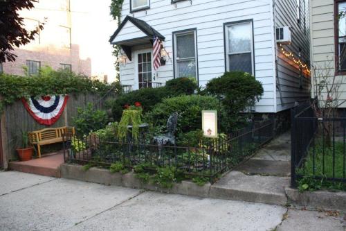 A charming house with a garden, featuring a bench, plants, and patriotic decorations, including an American flag.