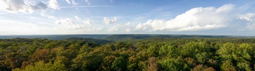 Panoramic view of lush green hills under a blue sky with scattered clouds.