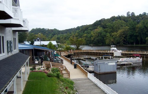 A scenic view of a marina with boats, wooden docks, and lush greenery along the water's edge on a cloudy day.