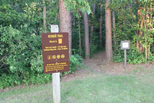 Sign for Redbud Trail, indicating a 1.5-mile loop, with a path leading into a wooded area.