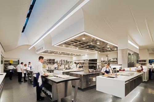 A modern kitchen with chefs working at stainless steel stations and a sleek, bright design.