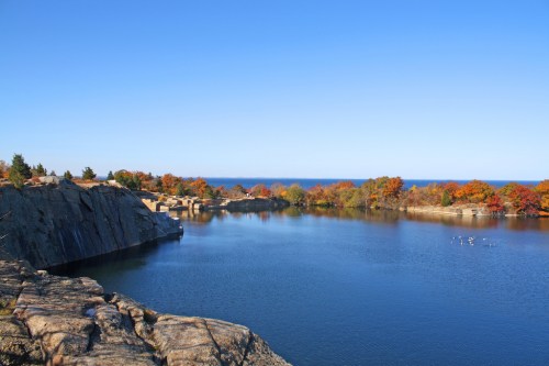A serene lake surrounded by colorful autumn trees and rocky cliffs under a clear blue sky.