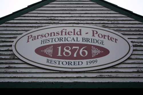 Sign on a wooden structure reading "Parsonsfield-Porter Historical Bridge, 1876, Restored 1999."