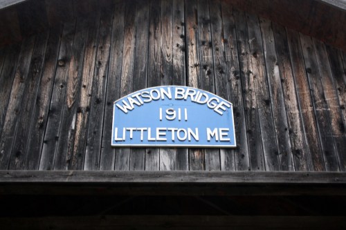 Sign on a wooden structure reading "Watson Bridge 1911 Littleton ME."
