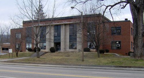 A brick building with large windows, labeled as a county court, surrounded by trees and grass.