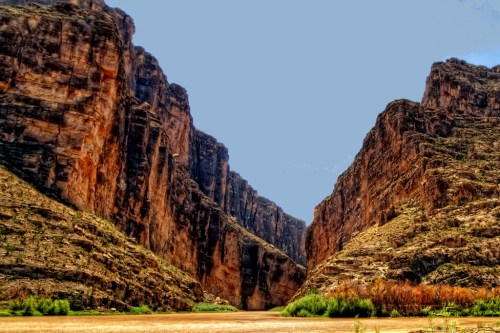 A stunning canyon landscape with towering rock formations and a clear blue sky above.