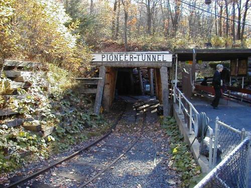 Entrance to the Pioneer Tunnel, surrounded by trees and autumn foliage, with a railway track leading inside.
