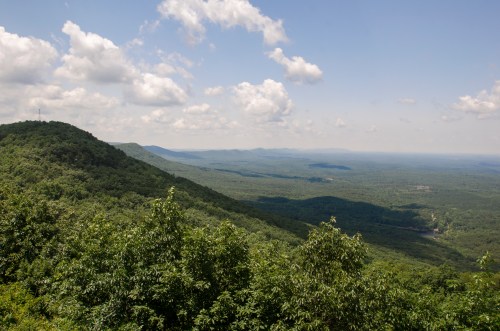 A panoramic view of lush green mountains under a partly cloudy sky.