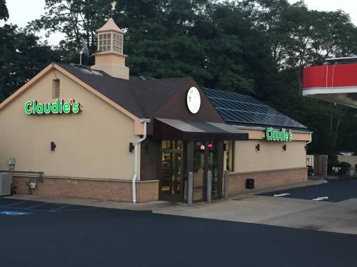 A small restaurant named Claudie's with a sloped roof and solar panels, surrounded by trees and a parking lot.
