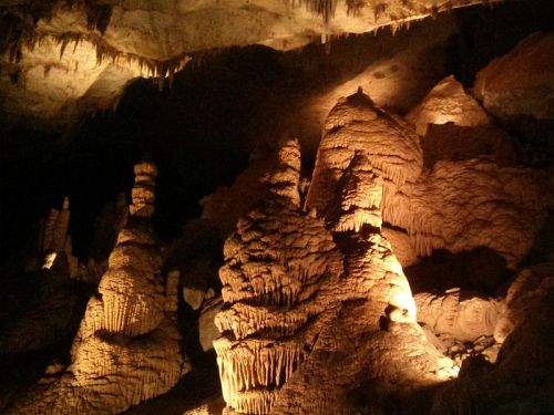 Stalactites and stalagmites illuminated in a dark cave, creating a dramatic natural landscape.