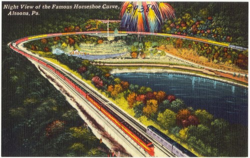 A vintage postcard depicting the Horseshoe Curve in Altoona, PA, with trains, a lake, and fireworks in the night sky.