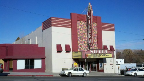 Historic Sierra Theater building with a colorful marquee and awnings, set against a clear blue sky.