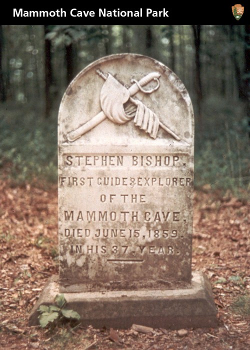 Gravestone of Stephen Bishop, first guide of Mammoth Cave, with a sword and flag design, in a wooded area.