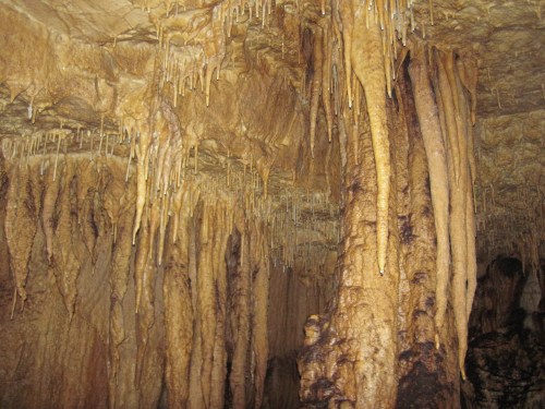 Stalactites and stalagmites in a dimly lit cave, showcasing natural rock formations and textures.