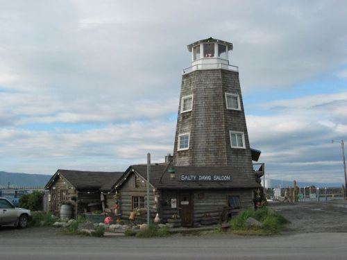 A rustic building resembling a lighthouse, labeled "Salty Dawg Saloon," set against a cloudy sky.
