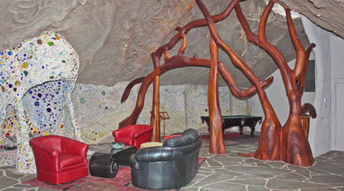 A unique interior featuring organic wooden structures, colorful walls, and modern furniture in a cave-like setting.