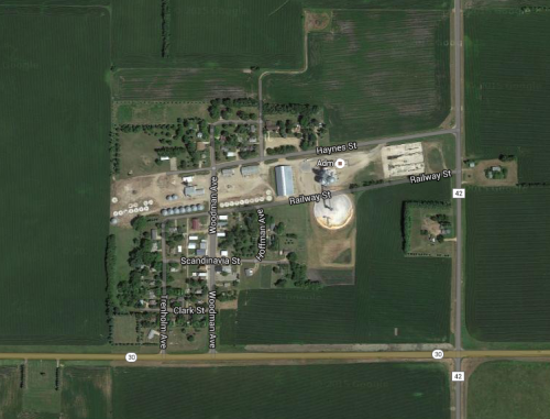 Aerial view of a small town with streets, buildings, and agricultural fields surrounding it.