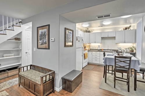 Cozy kitchen and dining area with wooden furniture, light walls, and a staircase in a modern home setting.