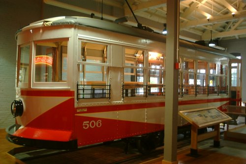 A vintage red and white streetcar displayed indoors, showcasing its windows and seating.